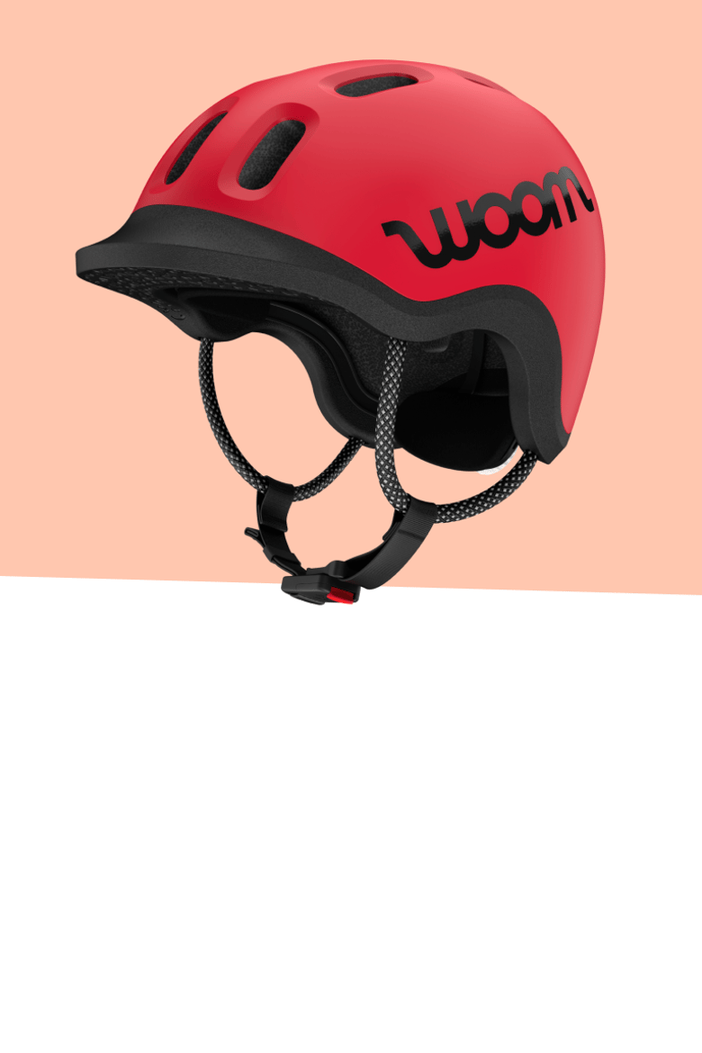 Red woom READY kids helmet in perspective view with ventilation slots and black chin strap.