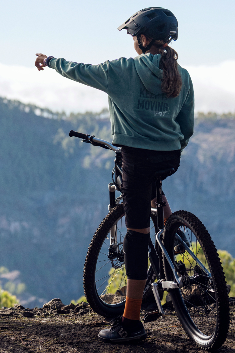 Child on a woom OFF MTB mountain bike looking over a valley and pointing.