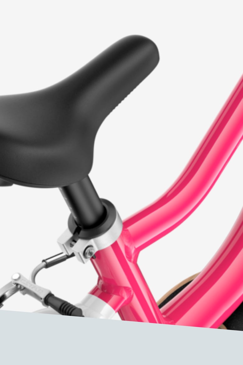 Close-up of the ergonomically profiled bicycle saddle with smooth top surface on a pink woom GO bike