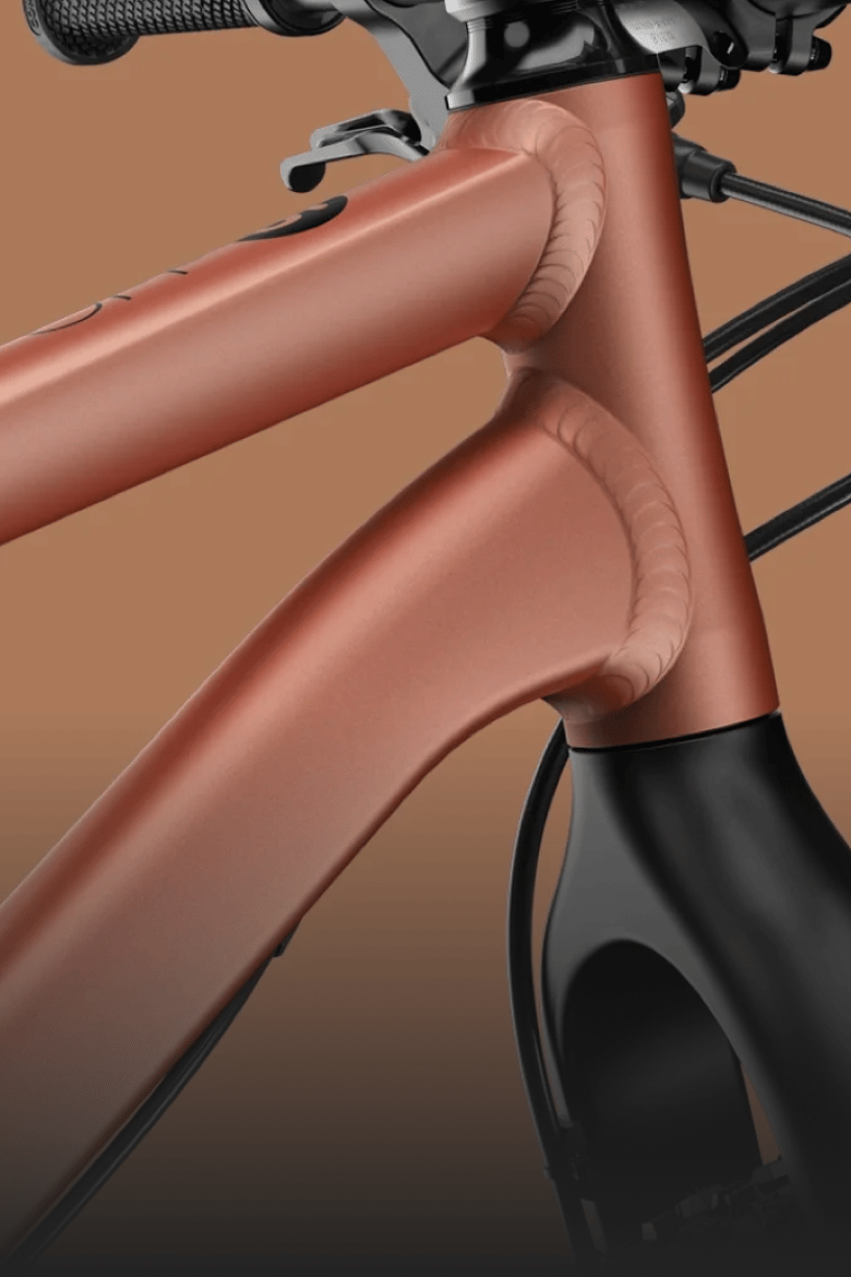 Detailaanzicht van het koperkleurige aluminium frame en de zwarte carbon vork op de mountainbike woom OFF