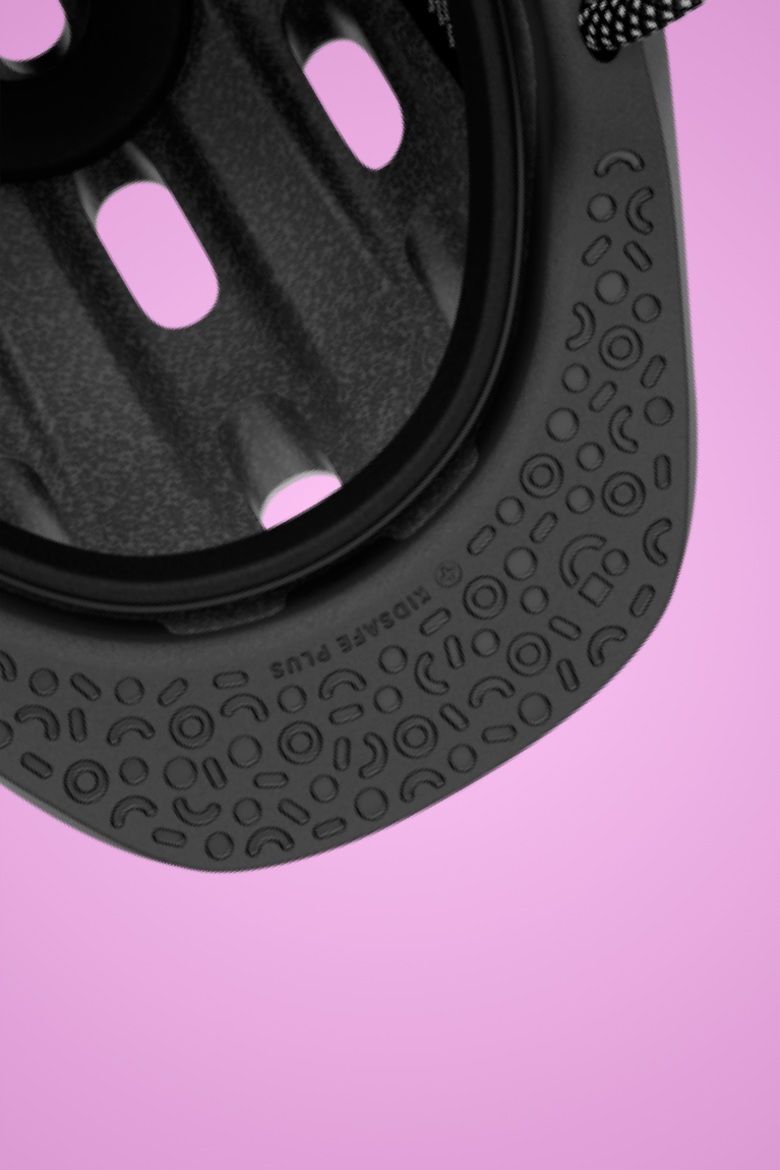 Detailaanzicht van de zwarte beschermende klep met motief van de READY-kinderhelm voor demping tegen een roze achtergrond"