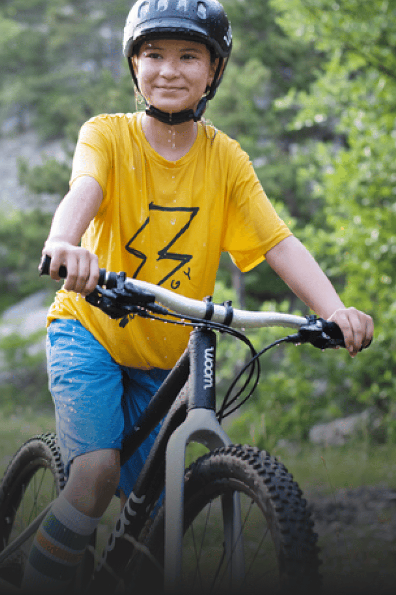 Kind met zwarte fietshelm op zit op een zwarte kindermountainbike van woom.