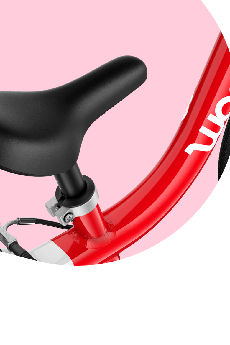 Close-up of the ergonomically profiled bicycle saddle with smooth top surface on a pink woom GO bike