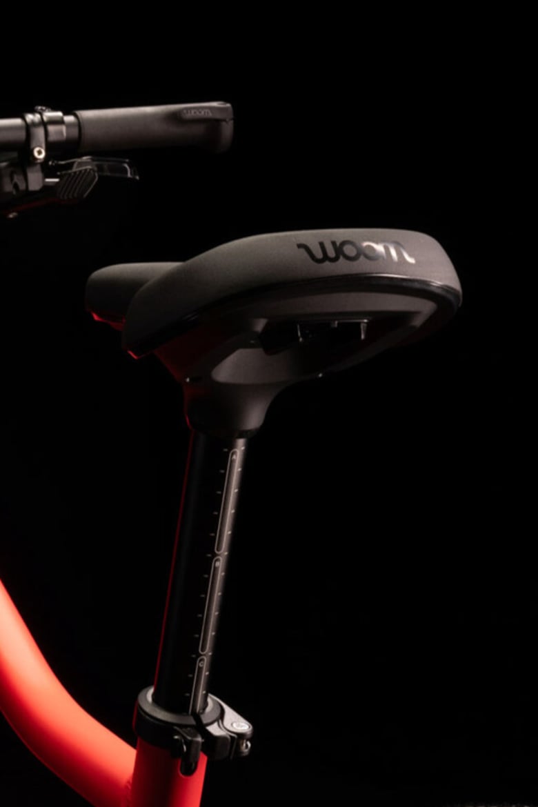 Gros plan d’une selle noire avec logo woom gravé à l’arrière, montée sur un vélo enfant woom EXPLORE.