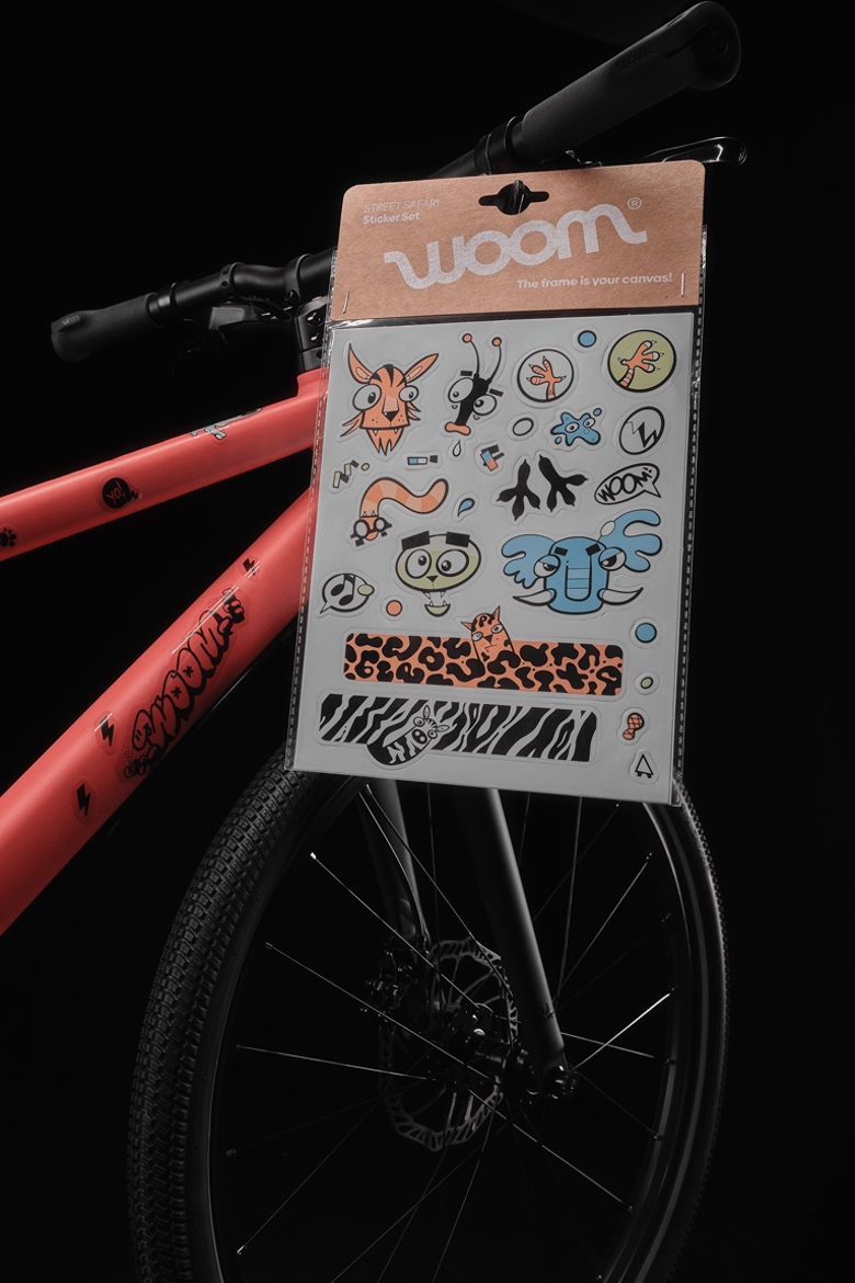 Vélo woom EXPLORE rouge avec stickers noirs transparents. Kit de stickers fermé sur le guidon.