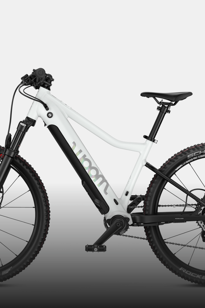 Profile view of the woom UP e-mountain bike in cirrus cloud with suspension fork and knobby tires.