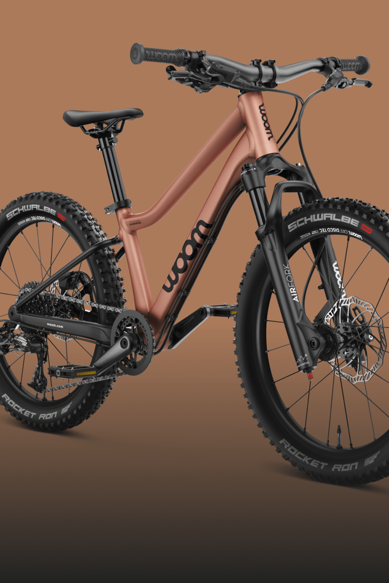 Side front view of the woom OFF AIR kids' mountain bike with front suspension in the color terra coppa