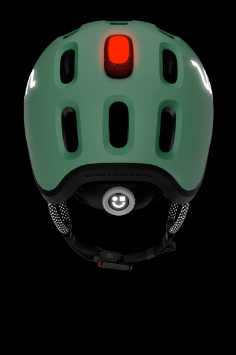 Vue de derrière du casque enfant READY de couleur verte dans le noir avec lampe de casque rouge et éléments réfléchissants