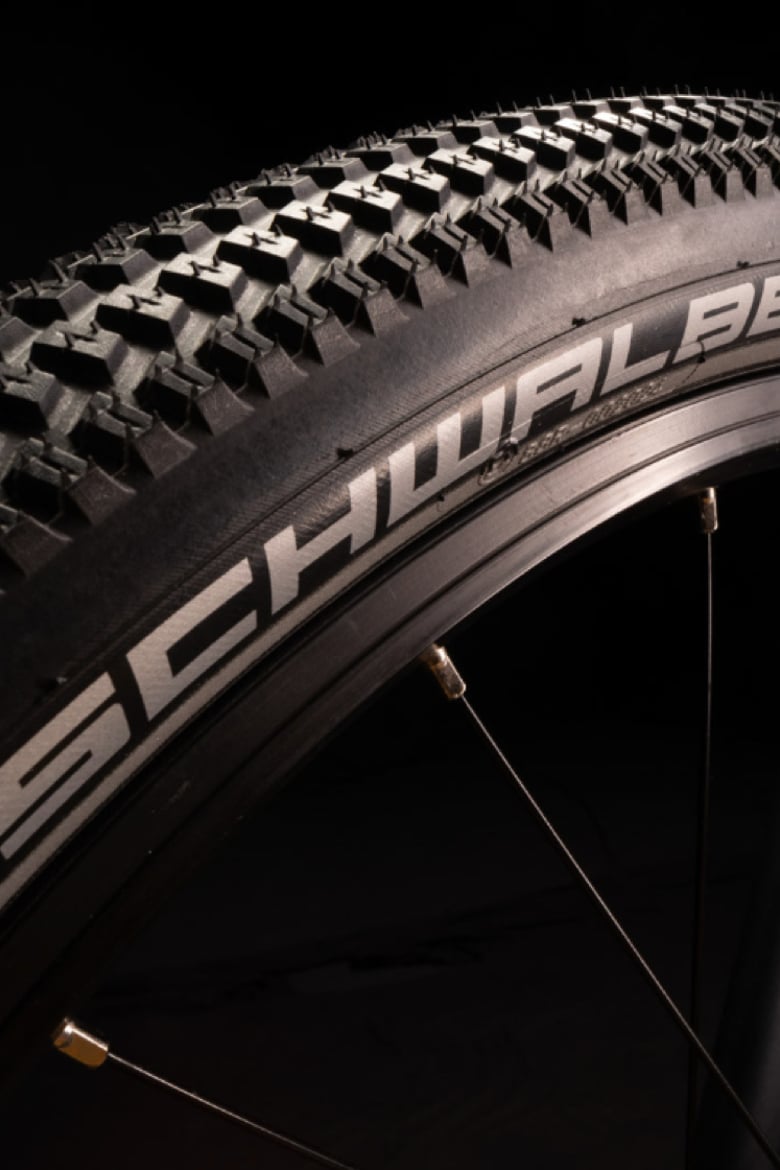 Gros plan d’un pneu de vélo noir sur le vélo enfant woom EXPLORE avec marquage Schwalbe blanc sur le flanc.