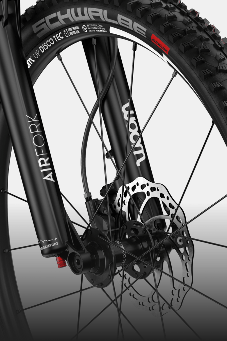 Close-up of the black air suspension fork and front wheel on the woom UP cirrus cloud.