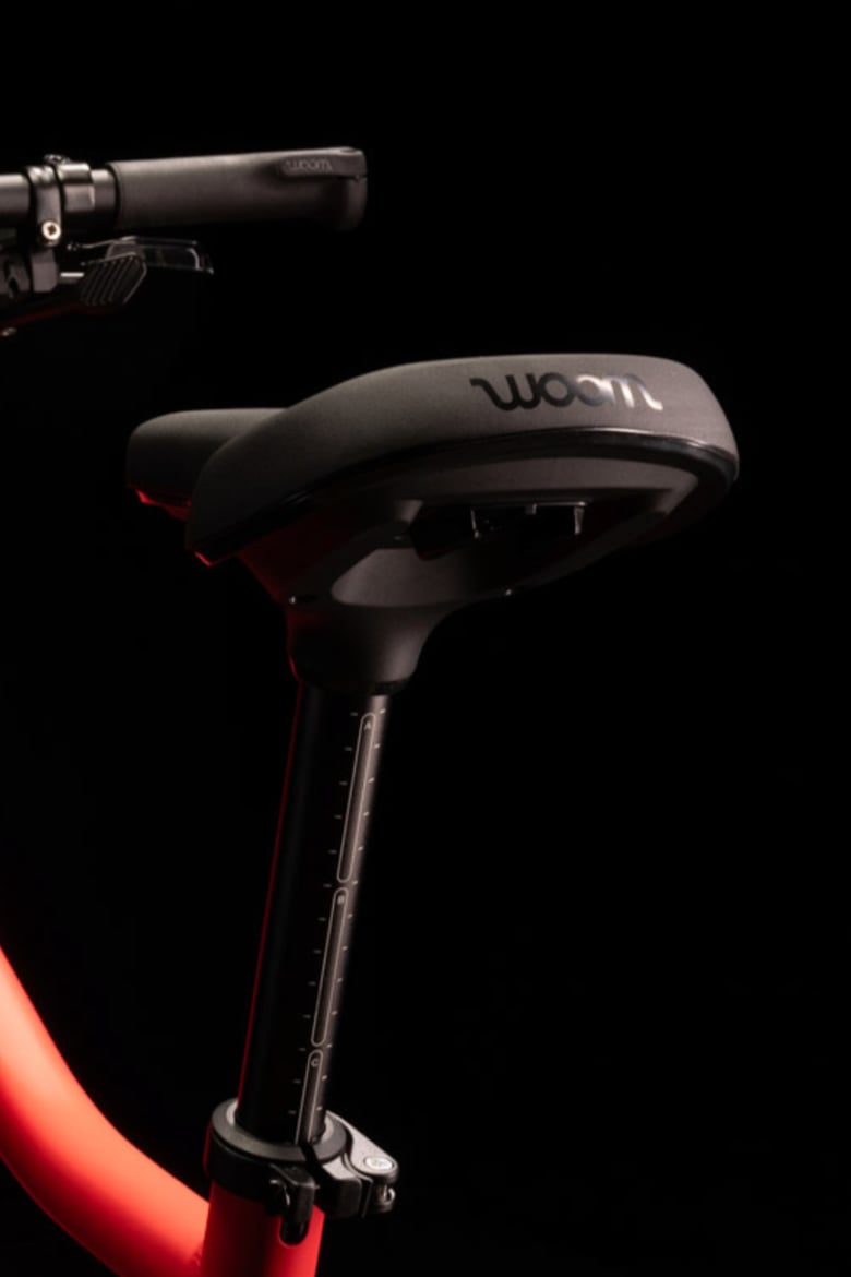 Close-up image of a black saddle with engraved woom logo on rear fitted onto a woom EXPLORE children's bike.