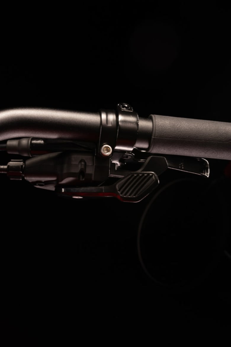 Gros plan du guidon noir woom EXPLORE avec une manette de vitesses à gâchette noire.