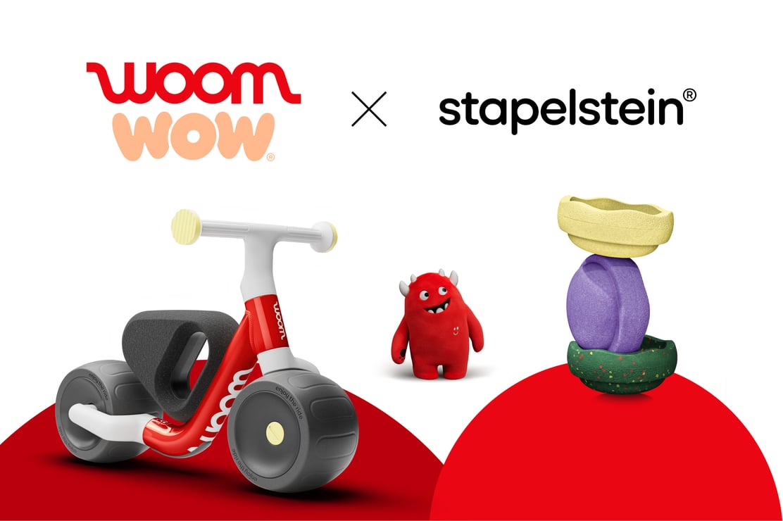 woom WOW x Stapelstein® Seasonal Edition collaboration banner featuring the red woom WOW balance bike, Buddy the red soft toy, and three stacked exclusive Stapelstein® Original Minis.