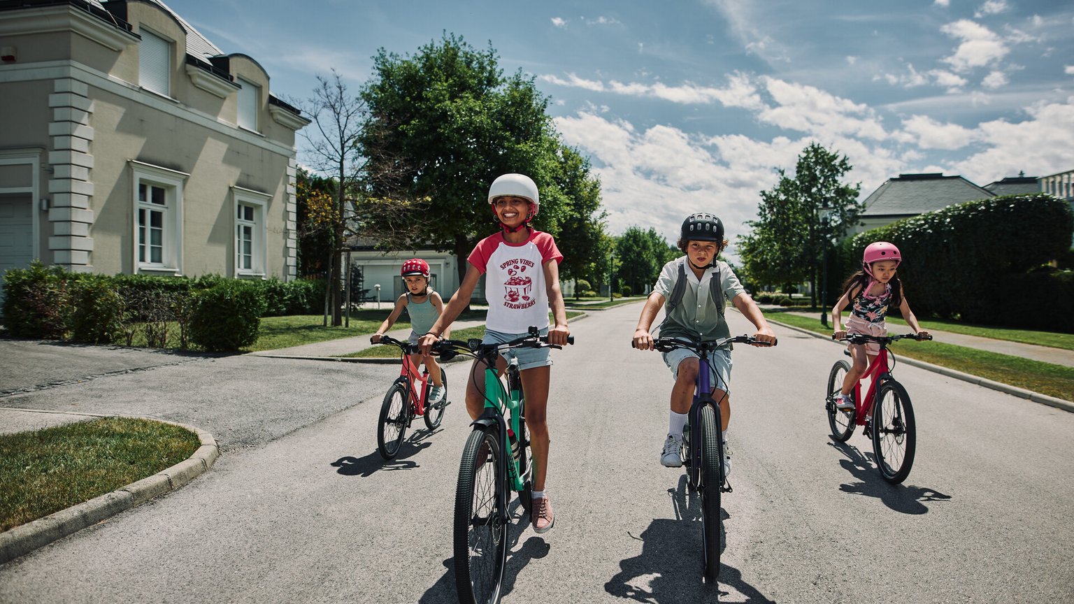 Four children are biking down the street on their bikes from the Austrian brand woom.