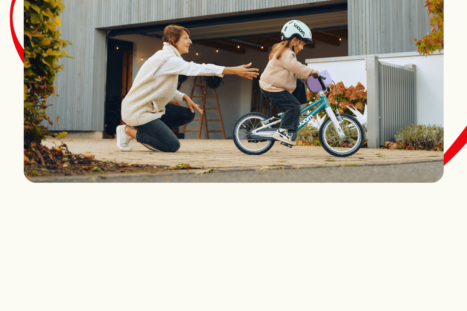 Ein Familienmitglied hilft einem Mädchen bei den ersten Fahrversuchen mit ihrem neuen Fahrrad woom GO.