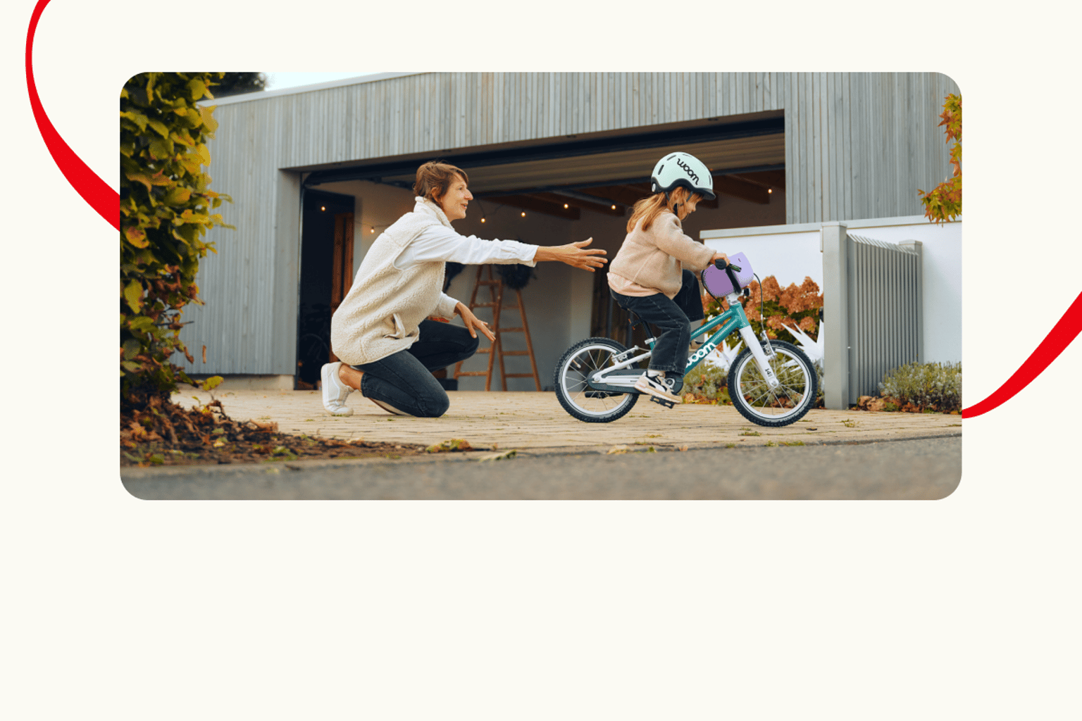 A family member supports a young girl as she enjoys her first moments with a new woom GO bike.