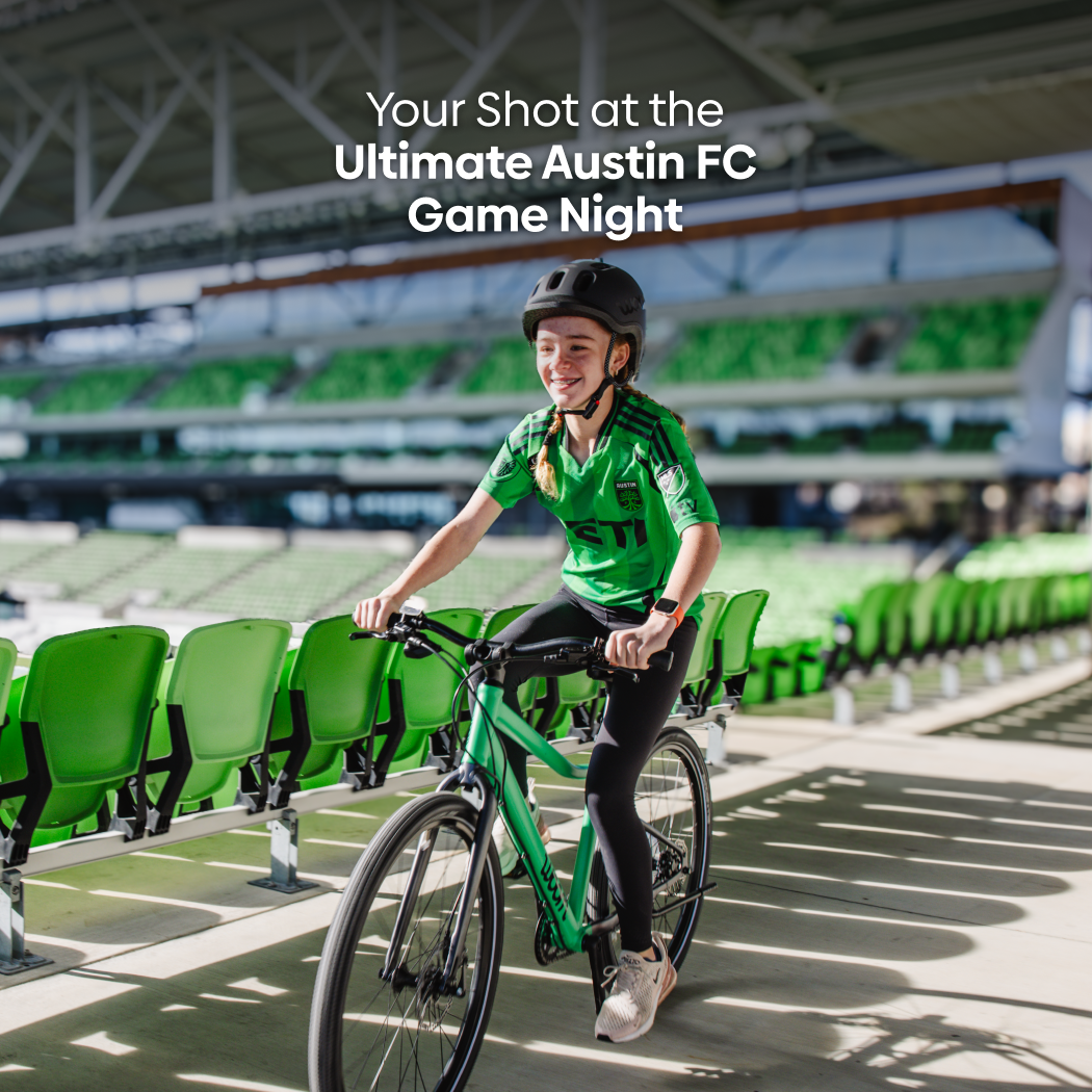 A preteen girl rides a jungle green woom EXPLORE bike through Q2 Stadium, home of Austin FC, with overlay text reading: Your Shot at the Ultimate Austin FC Game Night.