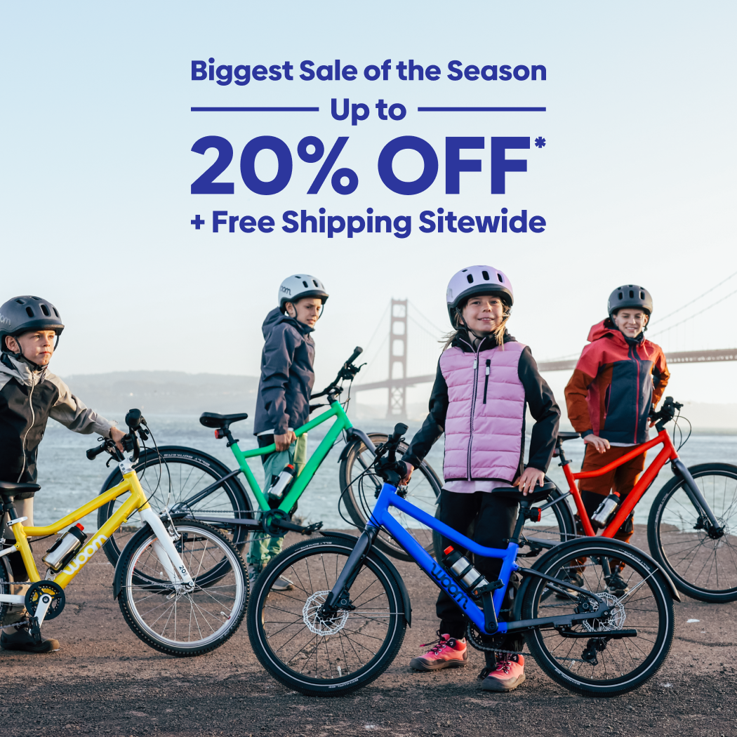 Kids pose with their colorful woom GO and EXPLORE bikes in front of the Golden Gate Bridge on a chilly day. Text over the image reads “Biggest Sale of the Season: Up to 20% Off Plus Free Shipping Sitewide”