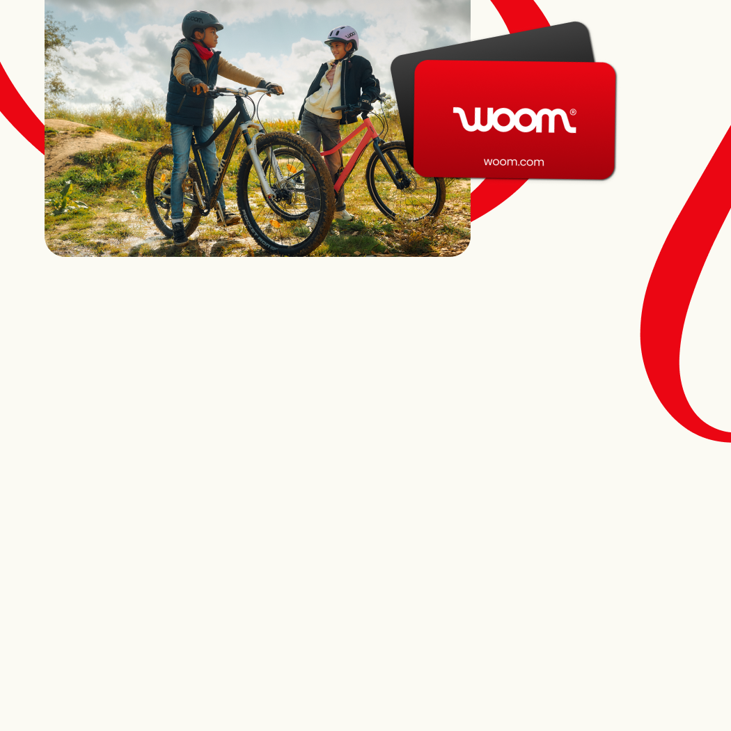 An image featuring two woom gift cards superimposed on a photo of two kids in a hilly outdoor setting. One is on a woom EXPLORE and the other is on a woom OFF, and they are chatting with each other while wearing woom READY Helmets. This is overlaid on a cream-colored background with red ribbons.