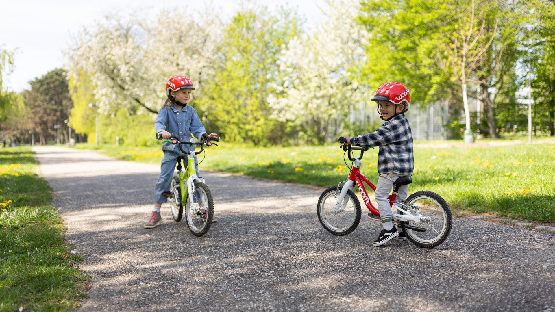 Links ein Mädchen auf einem woom Fahrrad, rechts ein Junge auf einem woom Laufrad.