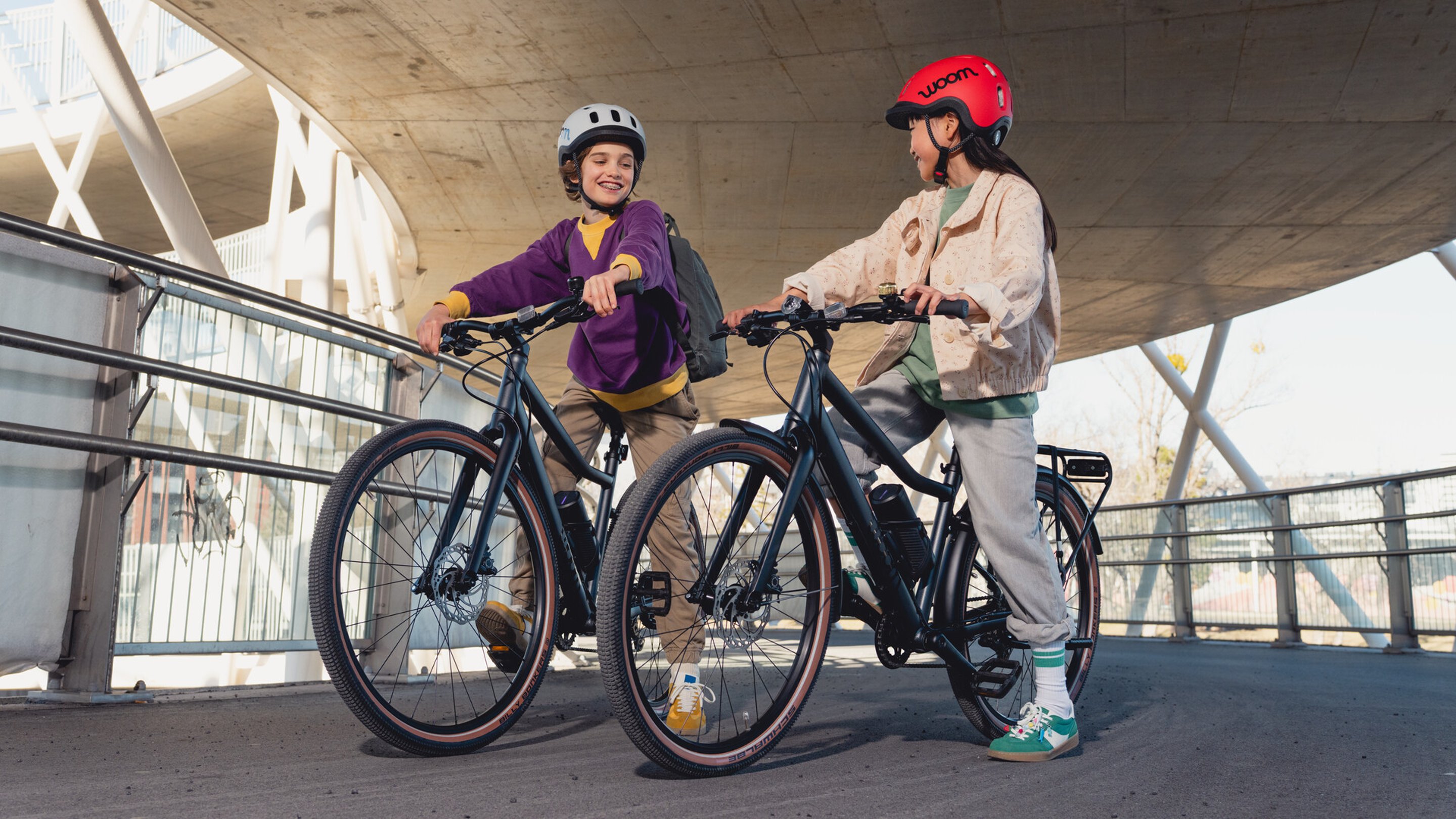 Ein Mädchen und ein Junge sitzen auf woom EXPLORE e E-Bikes.