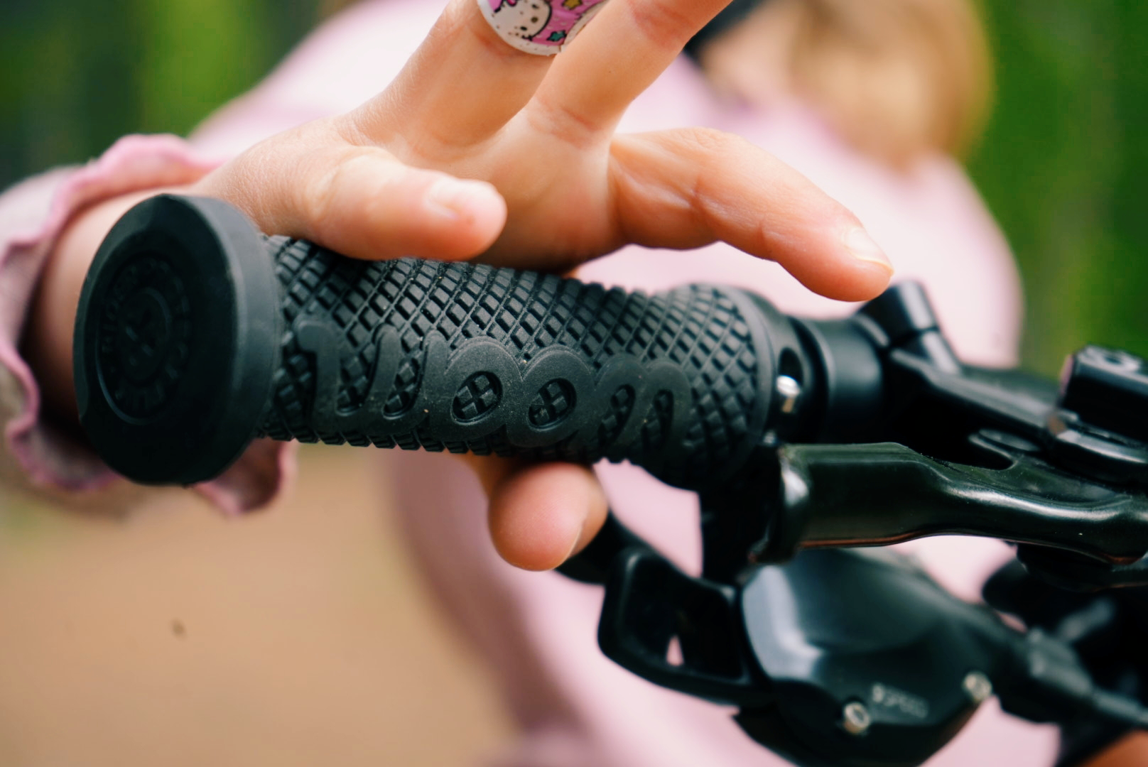 A close-up photo of a child’s hand adjusting its grasp of the handlebar grip on a woom bike.