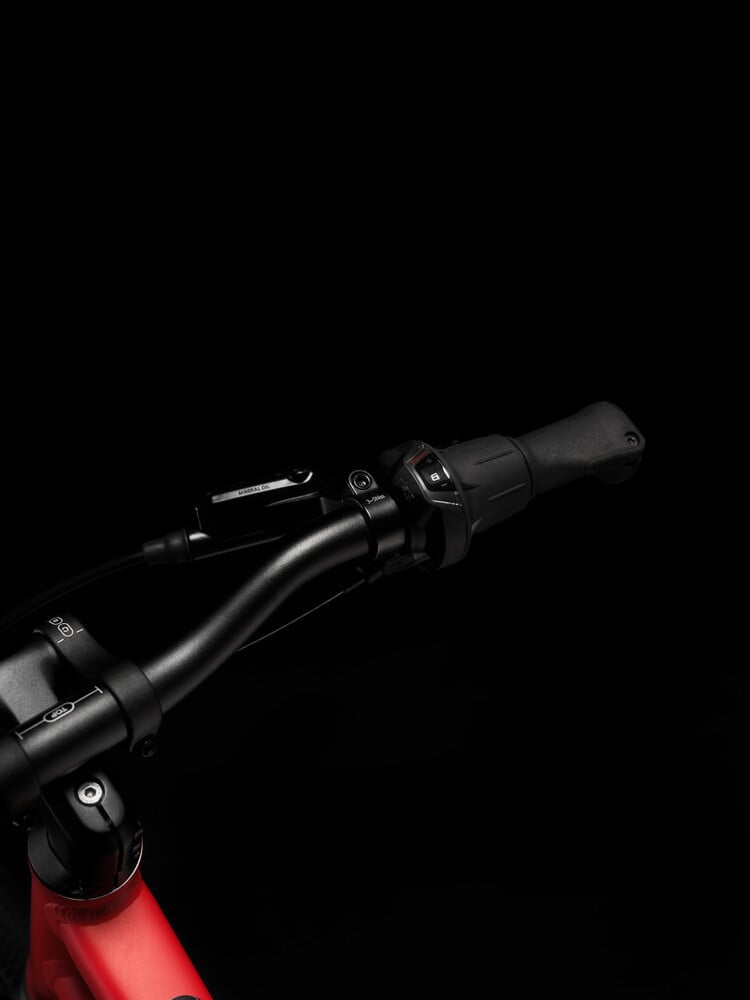 Close-up image of black woom EXPLORE handlebars and black Shimano twist shifter with gear indicator.