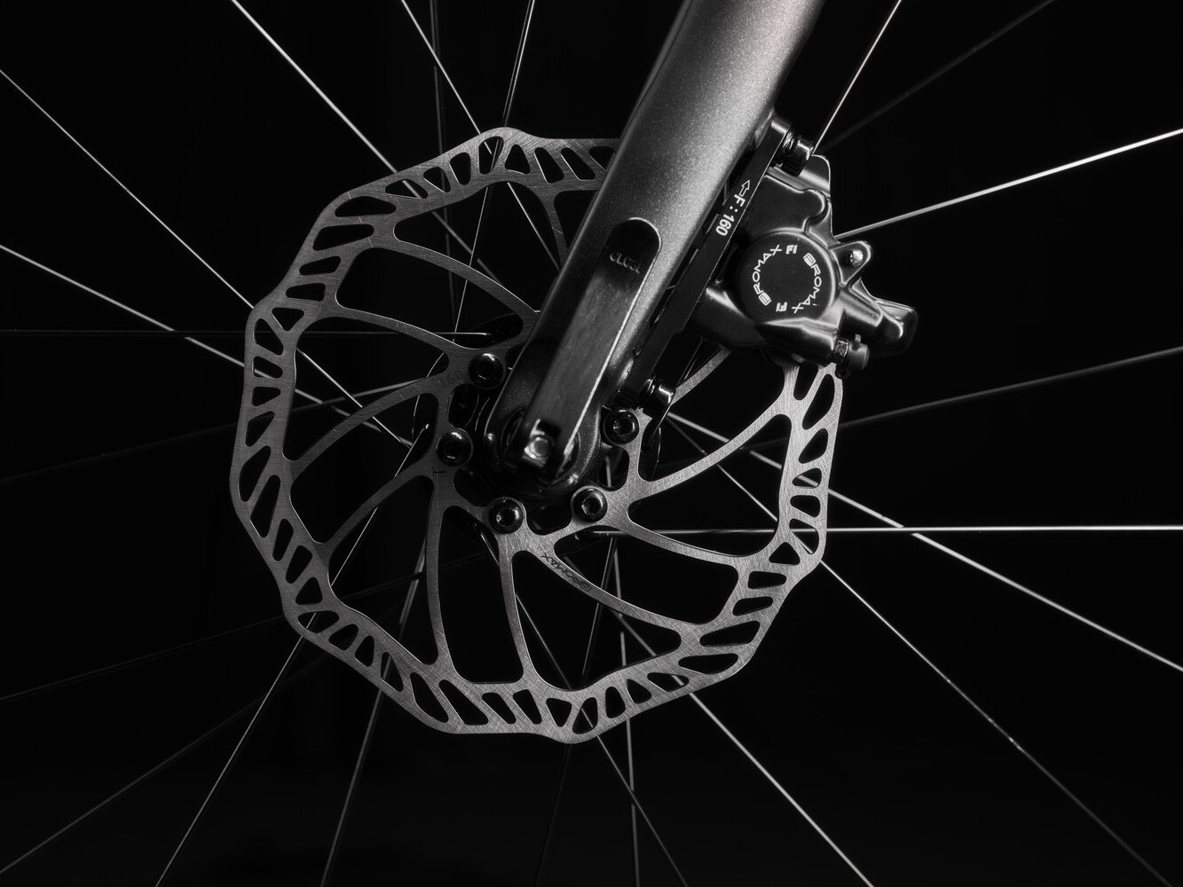 Close-up image of a silver disc brake rotor on the front wheel of a woom EXPLORE children's bike with black fork.