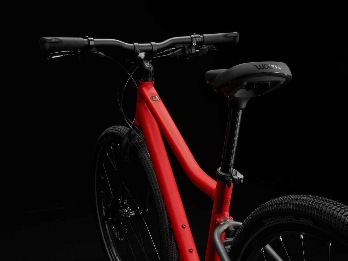 Red woom EXPLORE bicycle with black handlebars, black seatpost, black fork and black seatstays.