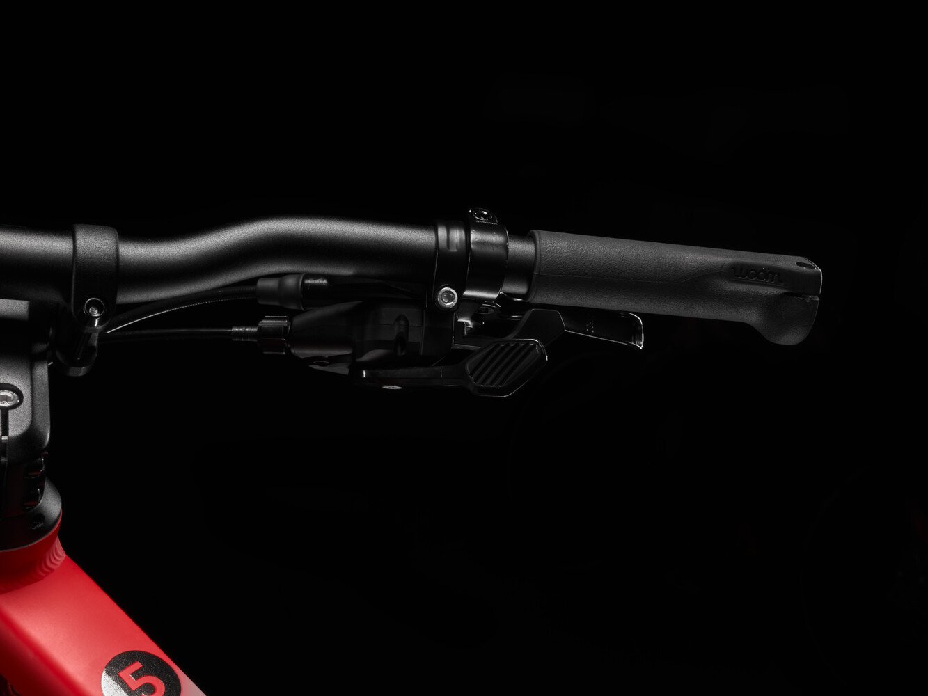 Close-up image of black woom EXPLORE handlebars and black trigger shifter.