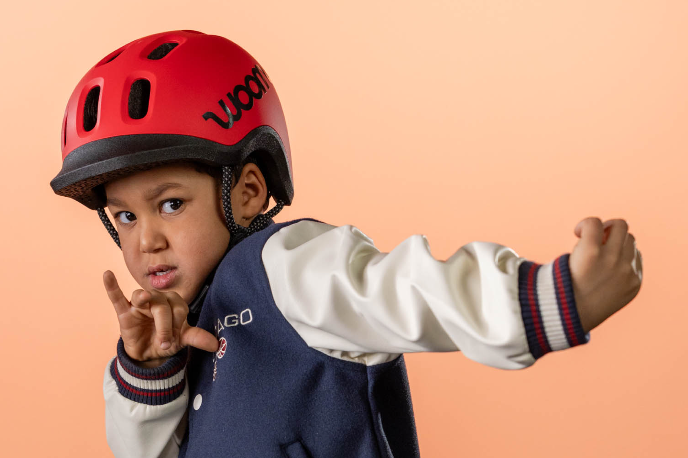 Un jeune enfant porte l’un des nouveaux casques woom rouges et prend la pause pour la photo.
