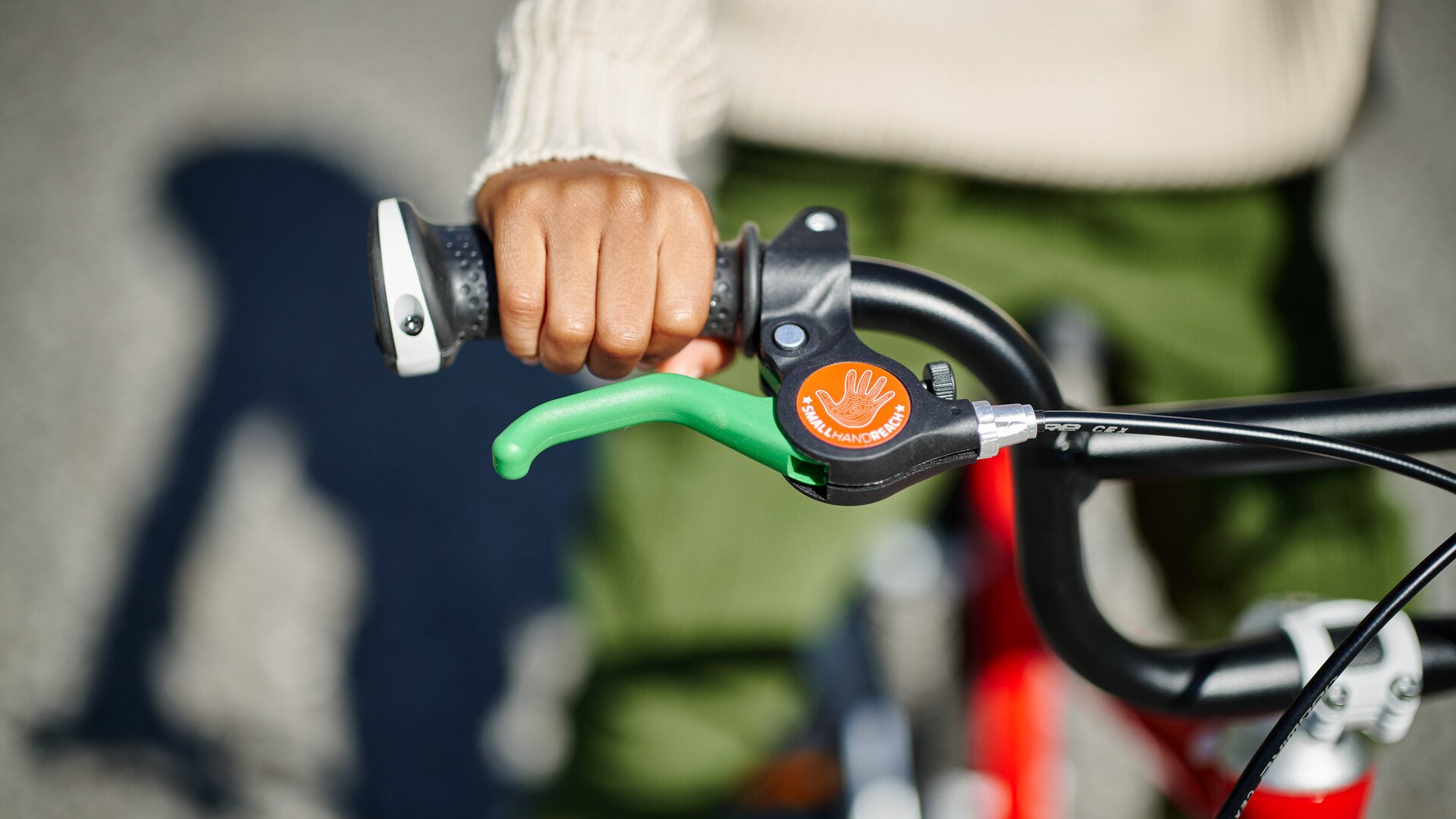 Detaljeret billede af et woom cykelstyr og et grønt bremsegreb.