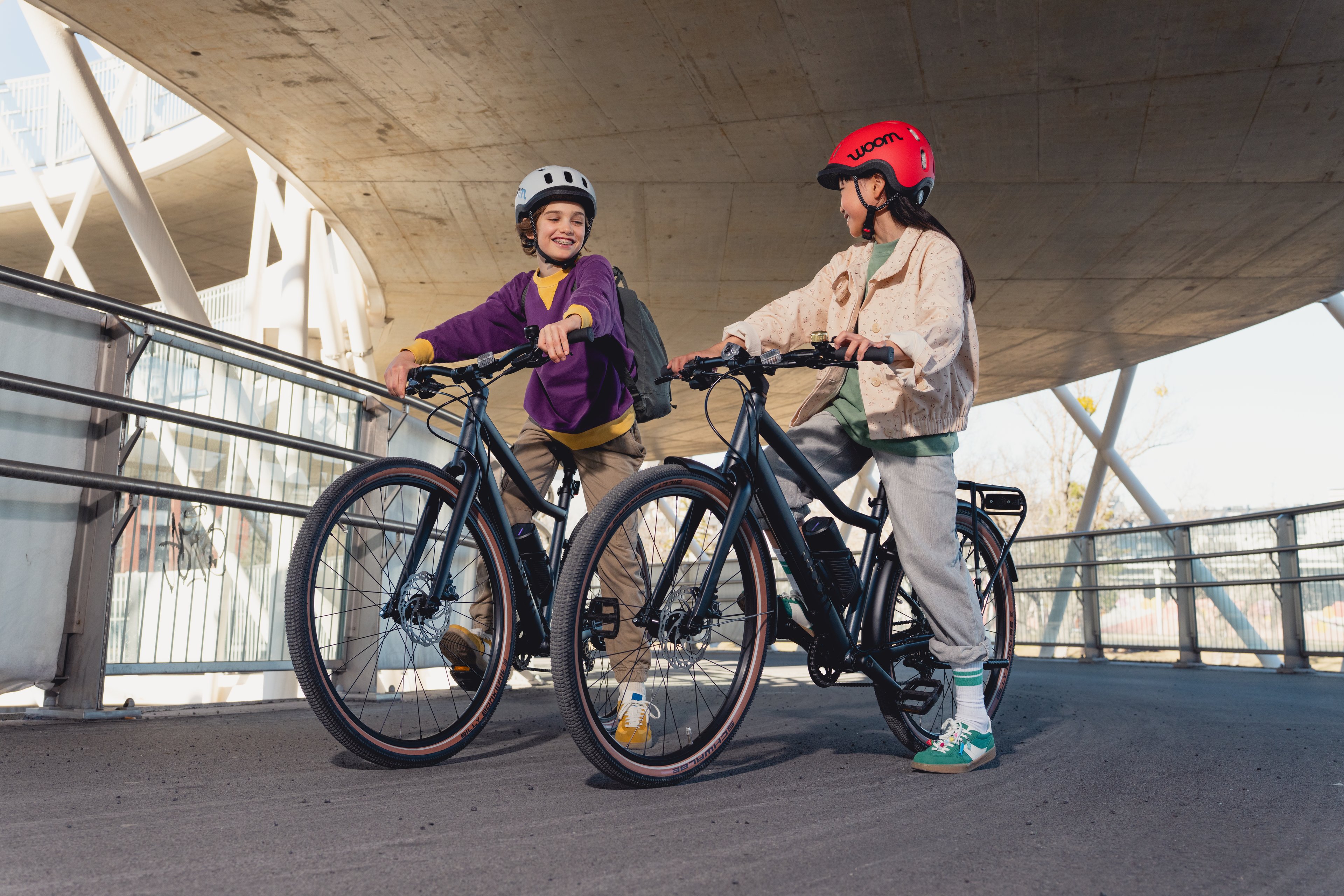 A girl and a boy are sitting on woom EXPLORE e e-bikes.