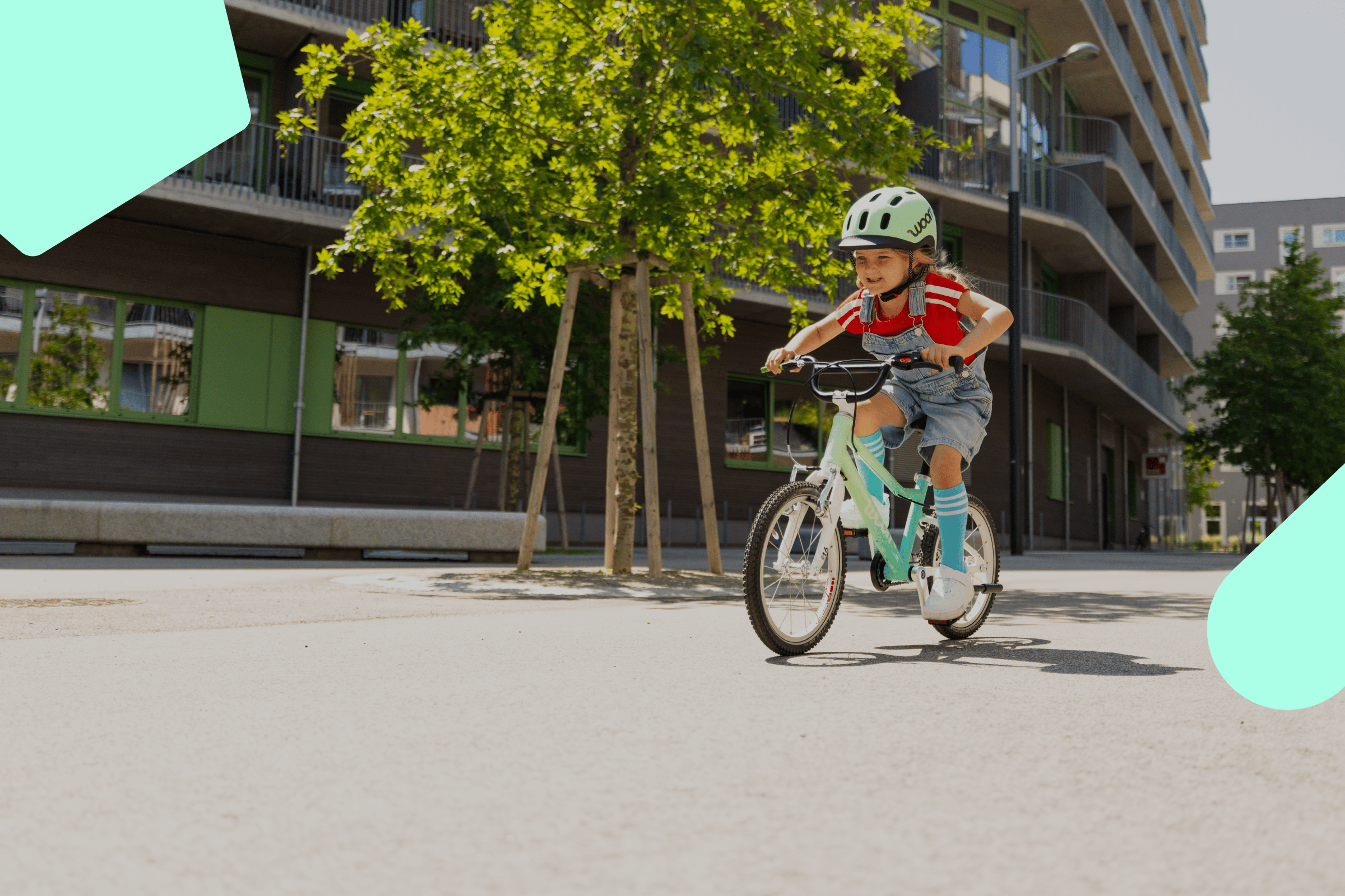 Kind mit READY Radhelm in Türkis auf dem Kopf fährt auf einem woom GO Kinderrad in der Limited Edition spearmint crush.