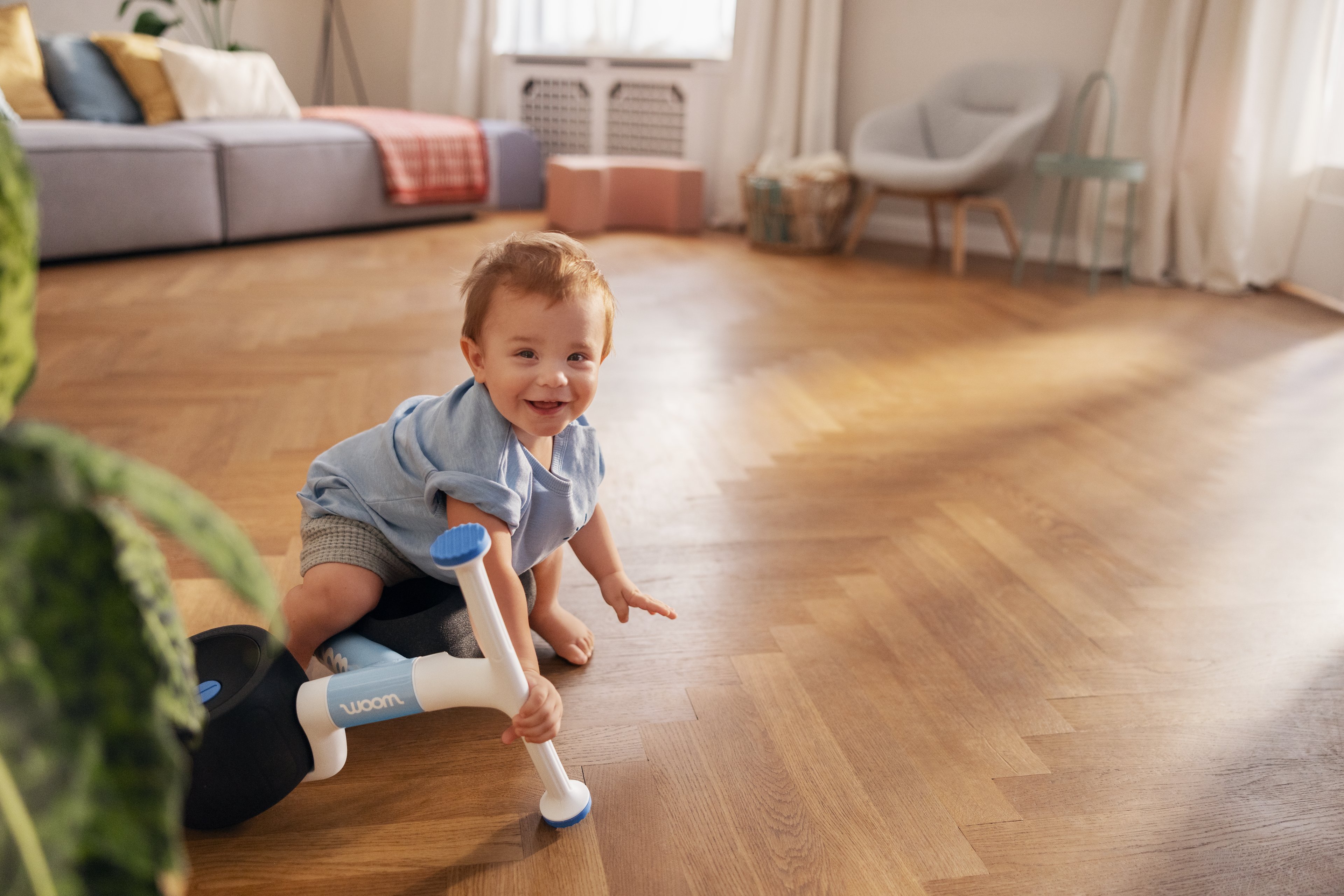 A young child is on the floor having fallen off their blue woom WOW balance bike. 
