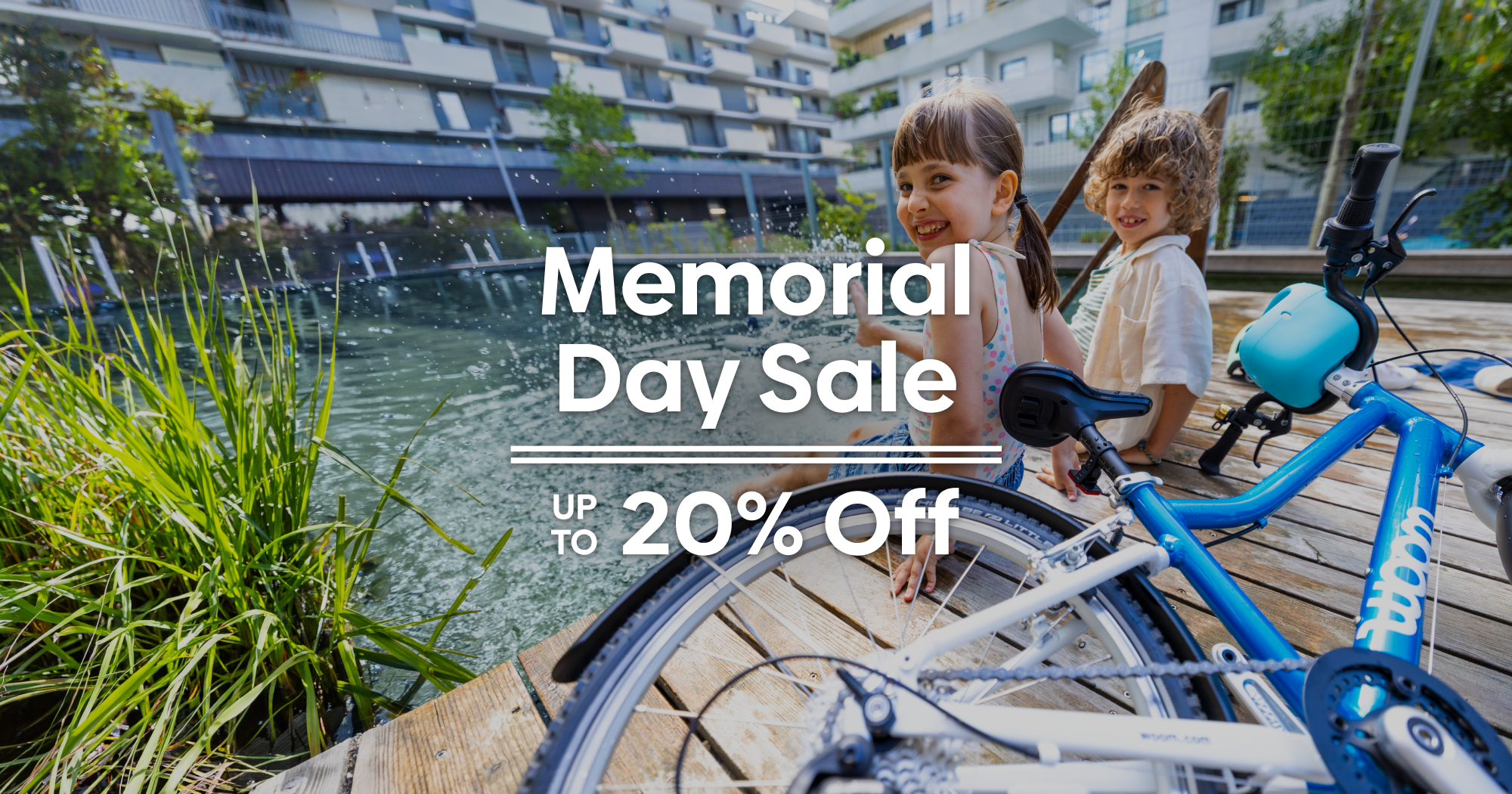 A boy and a girl sitting on a dock next to a metallic blue woom GO 4 laugh and splash their feet in the water. Text overlaying the image reads ‘Memorial Day Sale, Up to 20% Off.’