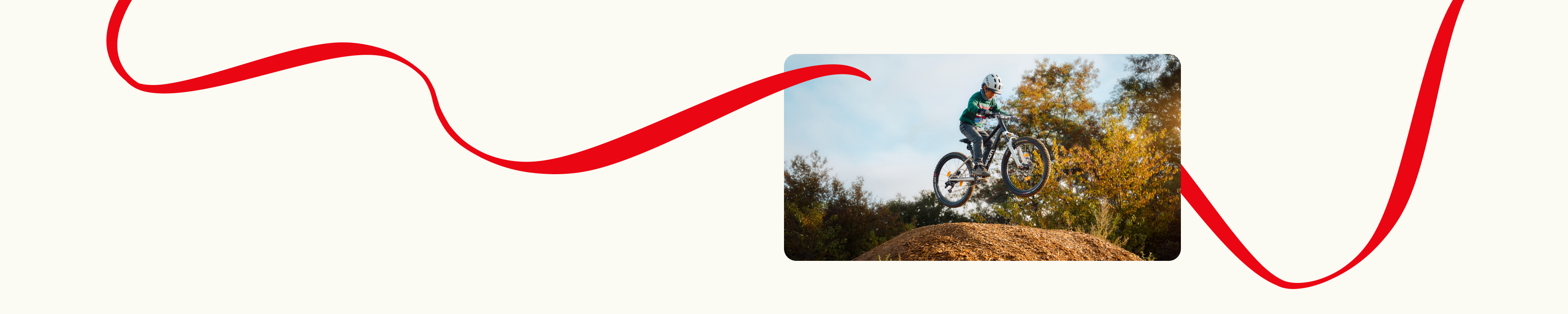 A child on a woom OFF mountain bike is jumping high over a dirt ramp with trees and sky in the background. Decorative red lines frame the scene.
