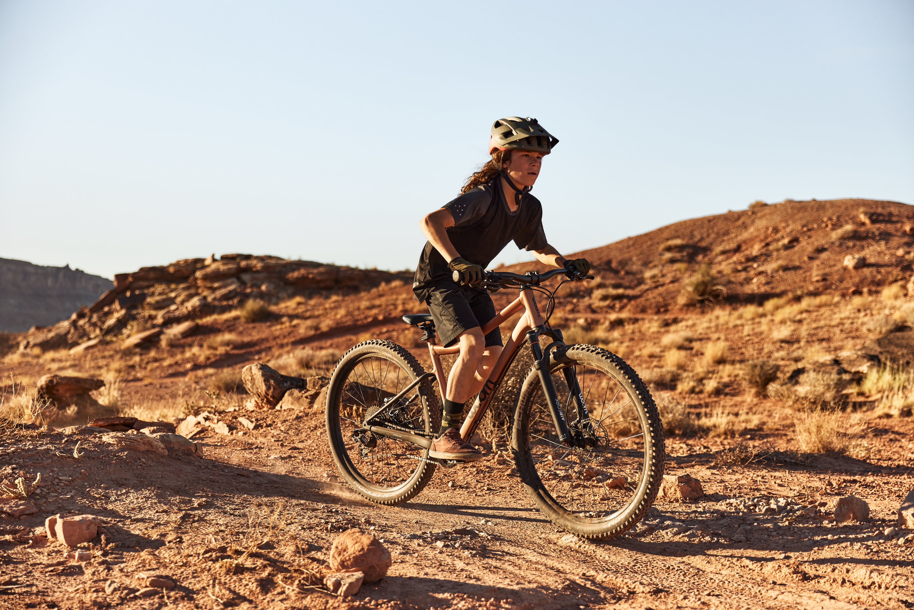 A boy riding a woom OFF AIR bike through mountainous canyons