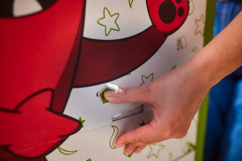 A close-up view of a hand pushing the green arrow on the Buddy photo stand through the opening and hooking it in place.