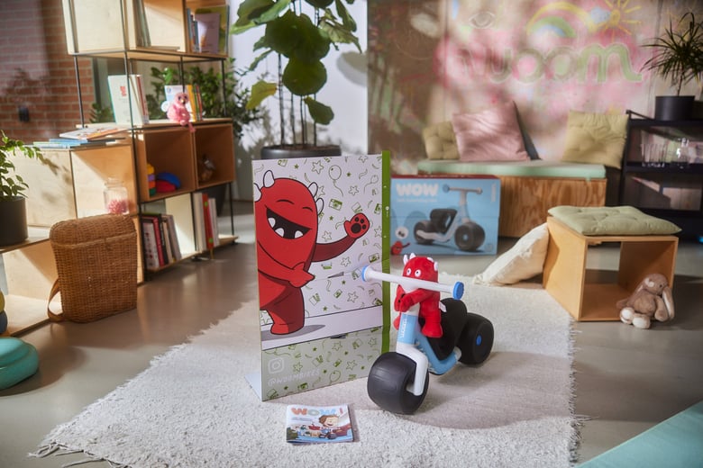 A fully assembled woom WOW self-balancing bike with the Buddy photo stand and six cones in a living room.