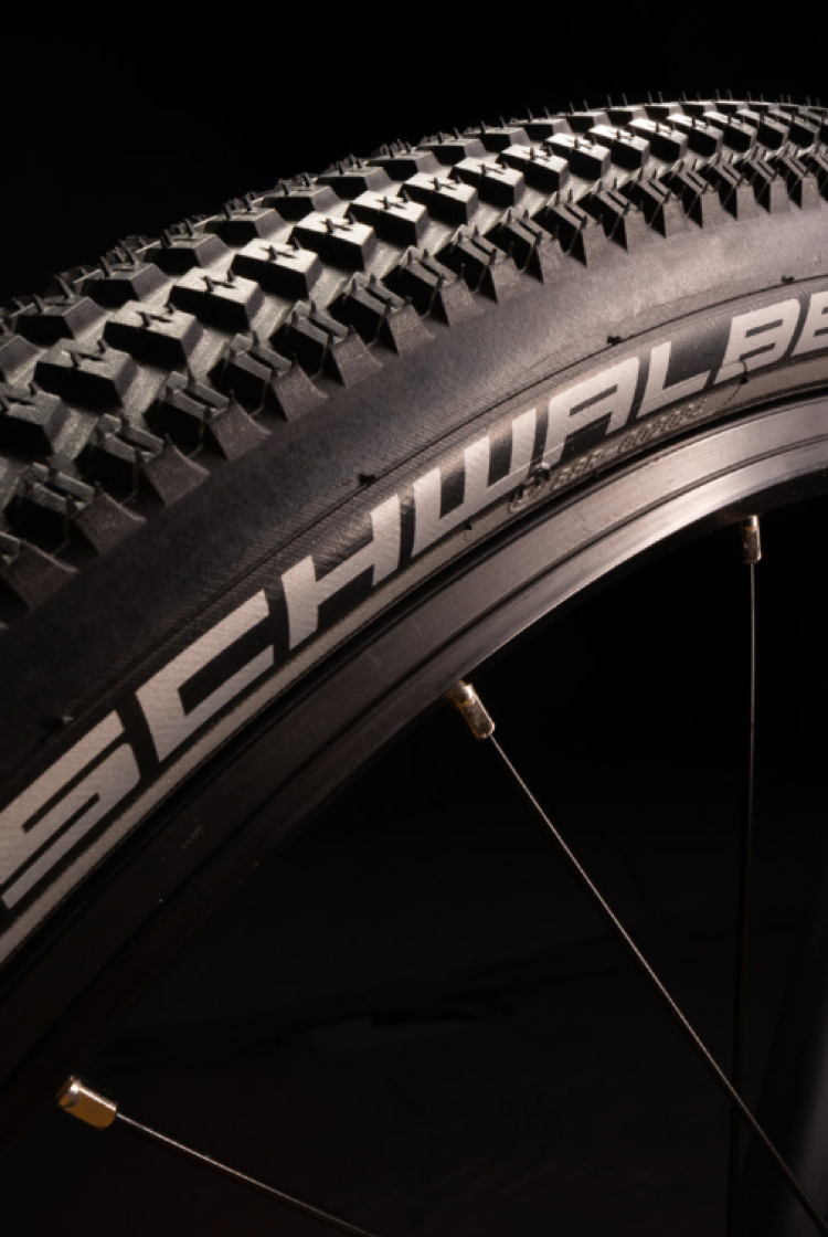 Nahaufnahme eines schwarzen Fahrradreifens am woom EXPLORE Kinderfahrrad mit weißem Schwalbe-Schriftzug auf der Flanke.