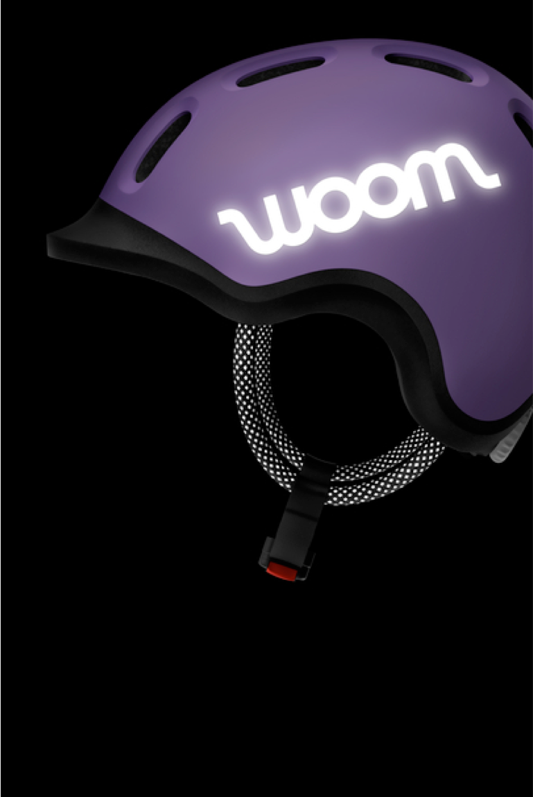 The lilac READY Kids' Helmet with reflective woom logos and straps, viewed from the side in the dark