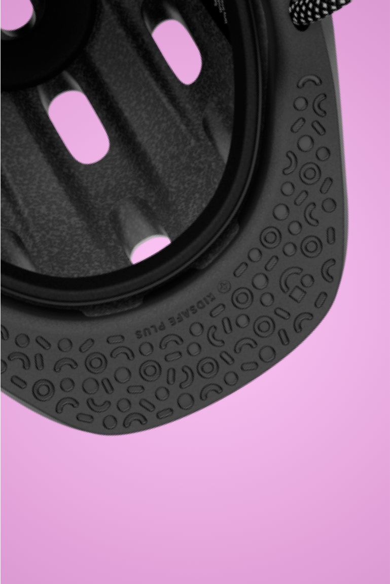 Close-up of the black, patterned, impact-absorbing protective visor on the READY Kids' Helmet on a pink background"