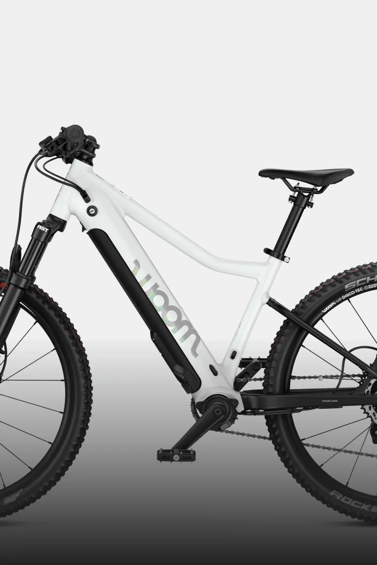 Profile view of the woom UP e-mountain bike in cirrus cloud with suspension fork and knobby tires.