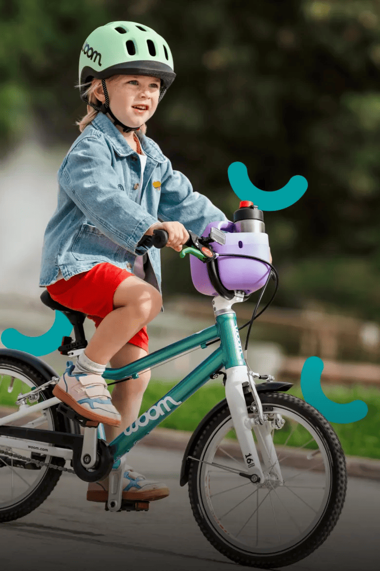 Kind mit grünem woom READY Kinderhelm auf einem türkisen woom GO 3 Bike.