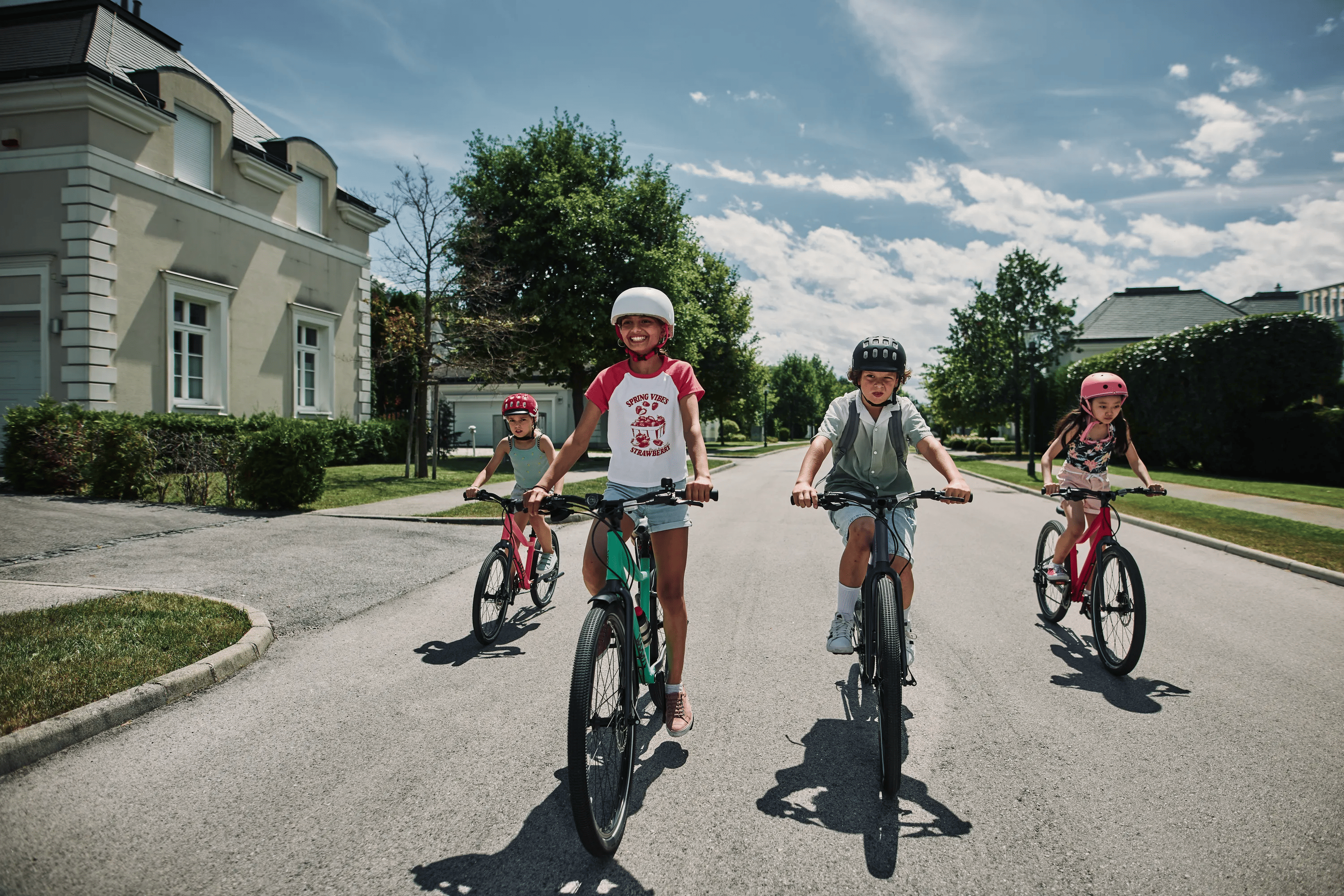 Quatre enfants roulent sur la route avec leurs vélos de la marque autrichienne woom.