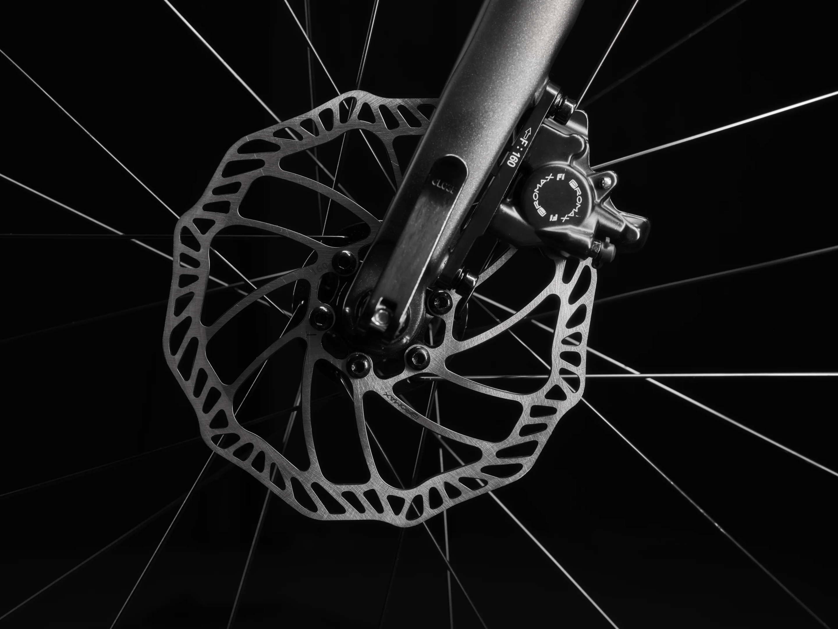Close-up image of a silver disc brake rotor on the front wheel of a woom EXPLORE children's bike with black fork.