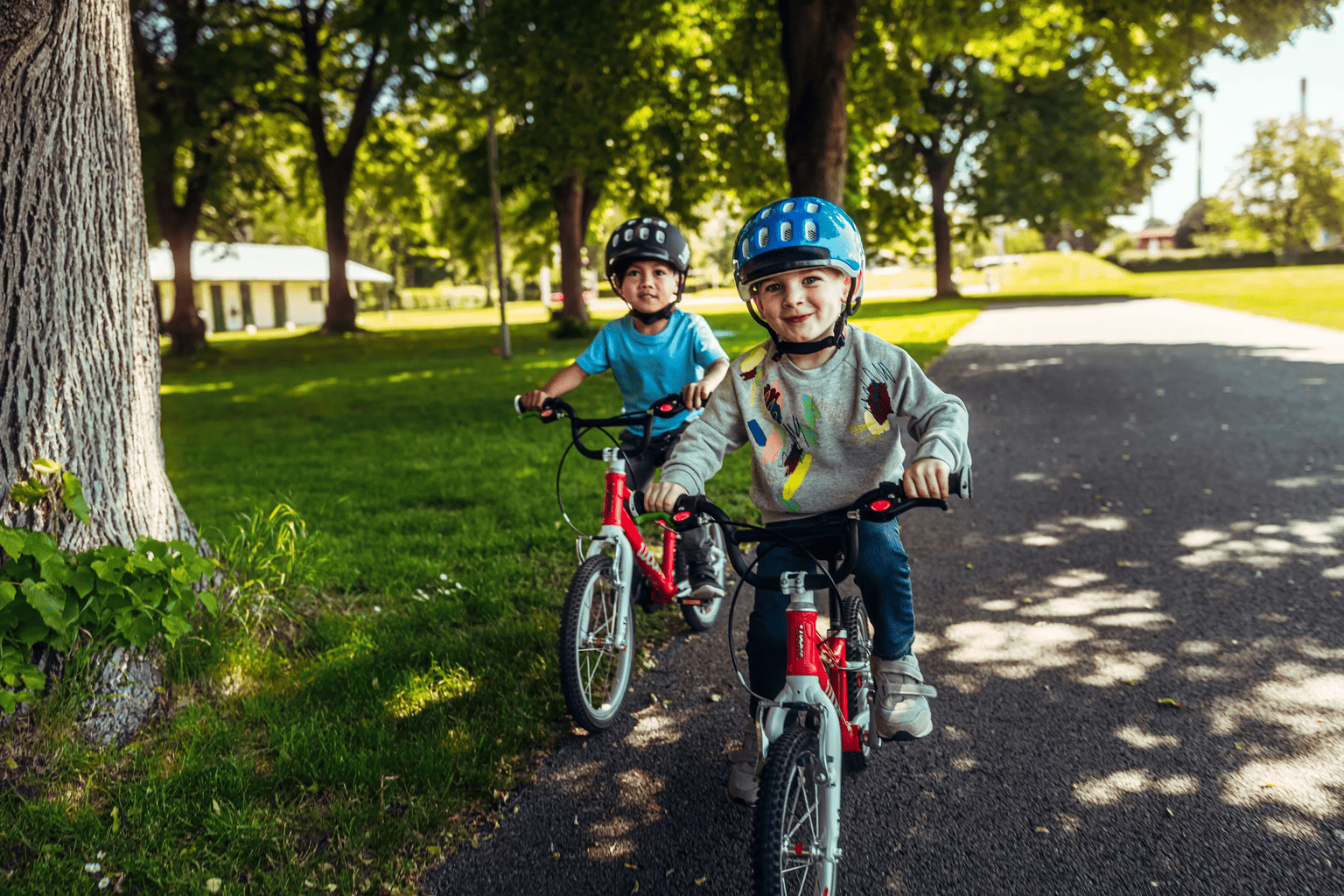 Zwei Kinder mit woom Helmen auf roten woom bikes