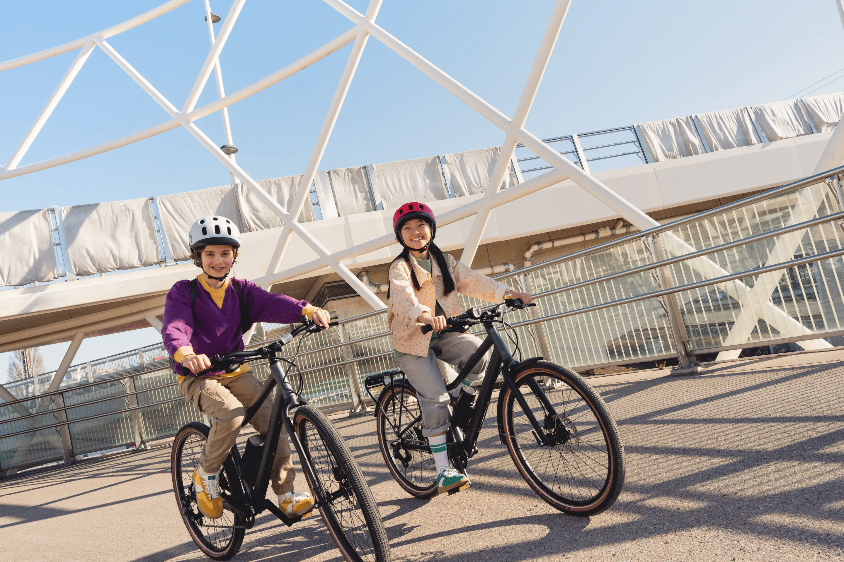 Zwei Kinder fahren nebeneinander mit woom EXPLORE e E-Bikes eine Parkhaus-Spindel hinauf.
