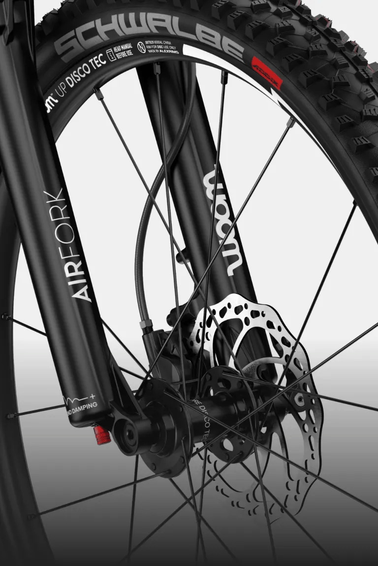 Close-up of the black air suspension fork and front wheel on the woom UP cirrus cloud.